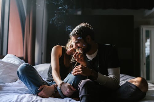 Free Man and Woman Sitting on Bed while Smoking Stock Photo