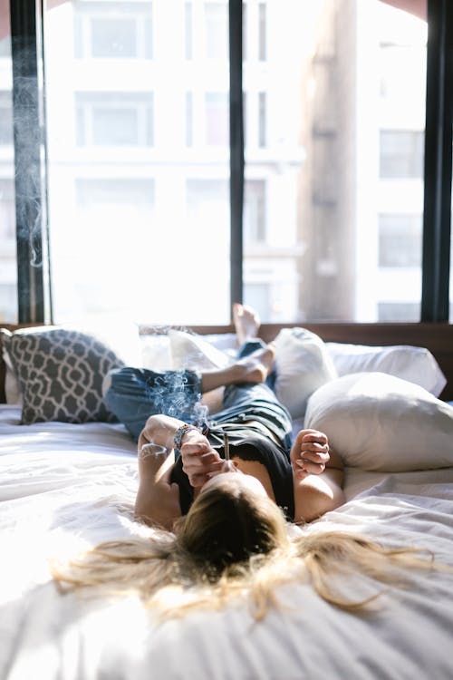 Free A Woman Lying on the Bed while Smoking Weed Stock Photo