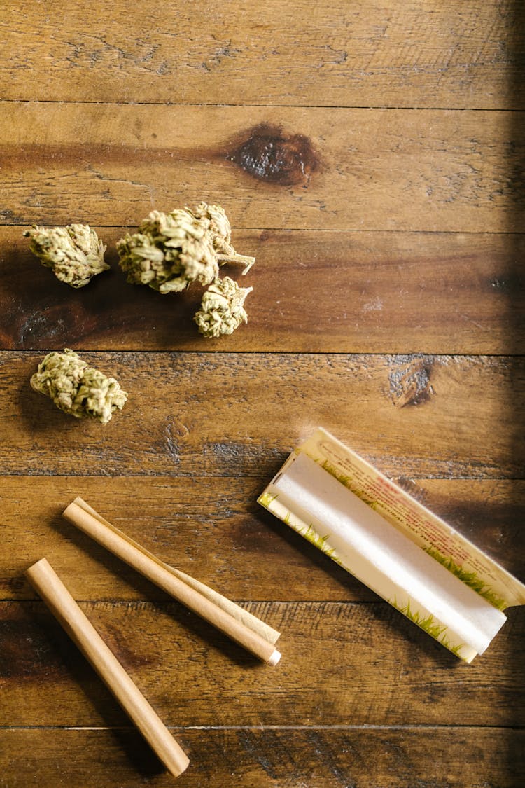 Rolled Paper And Cannabis Flower On Wooden Surface