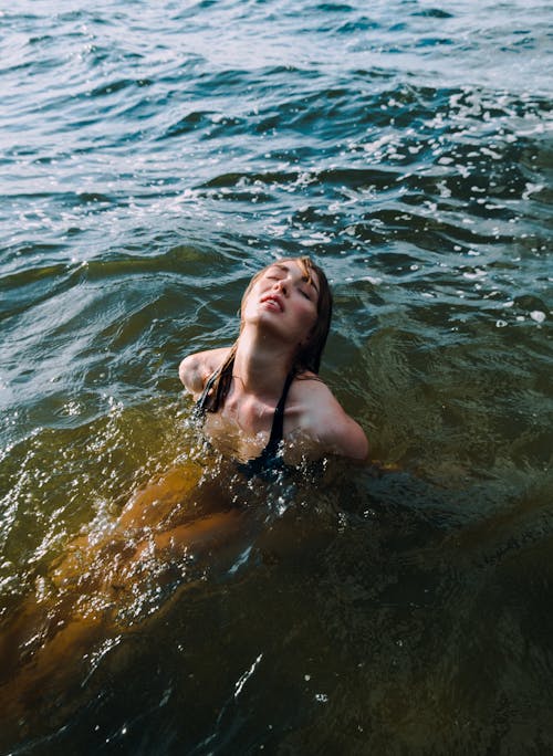 Woman in Black Bikini Swimming on Water