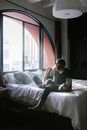 Woman in White Tank Top Sitting on Bed Using Laptop