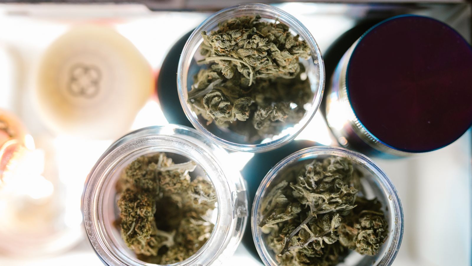 Close-up of cannabis buds in jars from above, highlighting marijuana storage.
