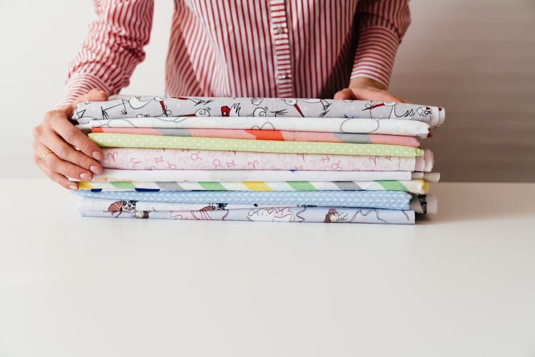 Person Piling Folded Printed Fabrics