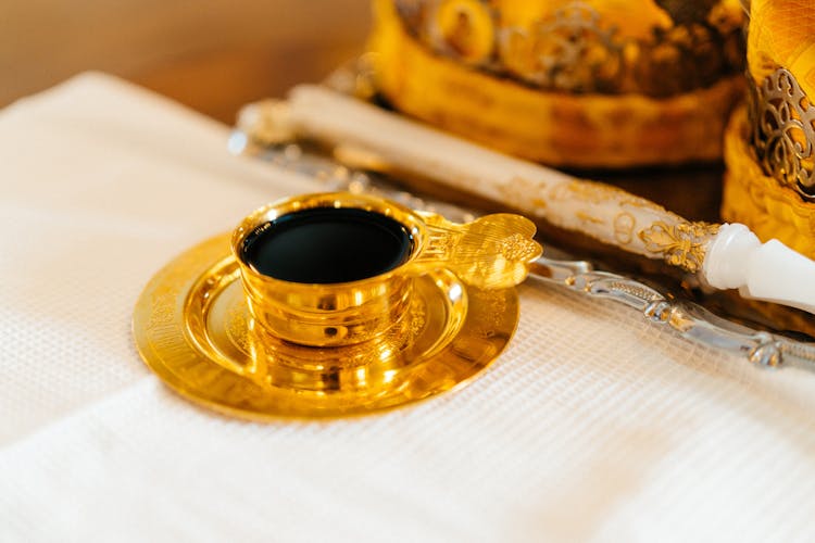 Close-up Of A Gold Cup With Black Coffee 