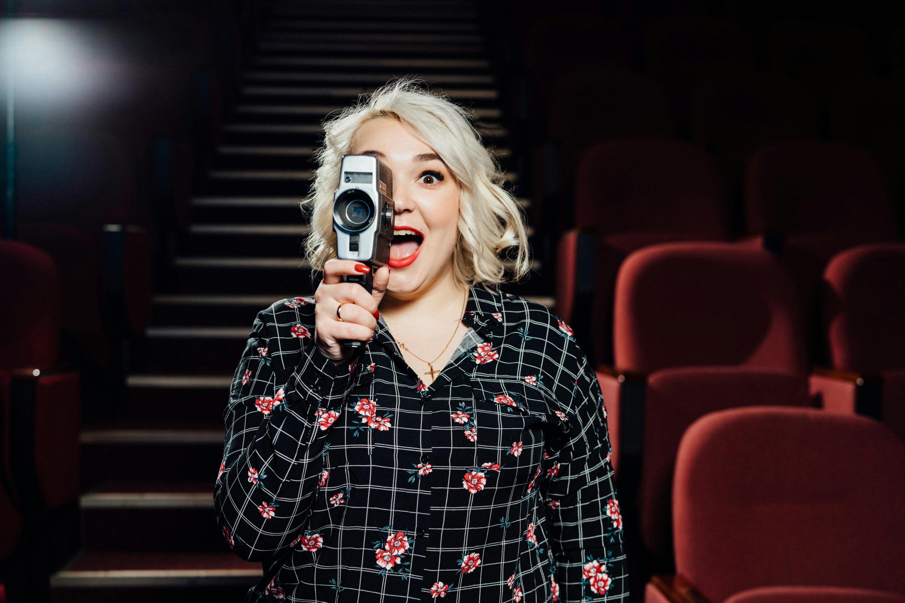 woman holding a camera camcorder in a movie theatre