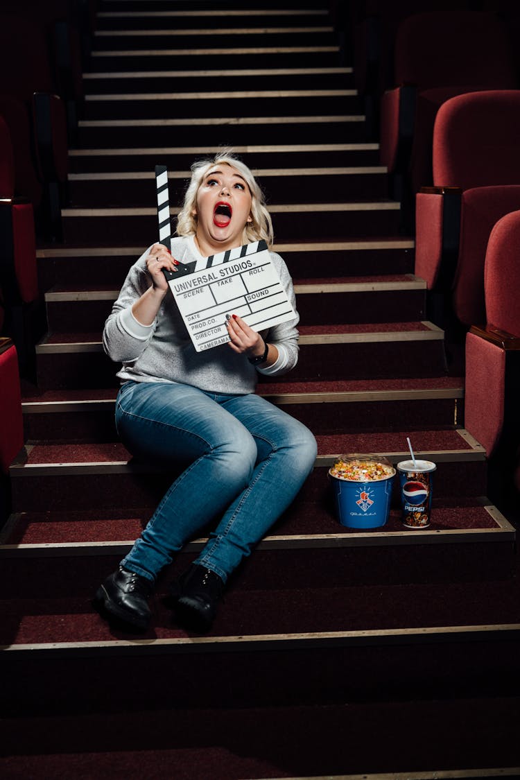 Woman Sitting On Stairs In Movie Theater With Clapper