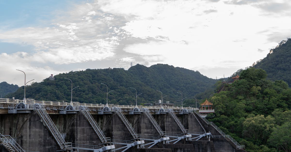 Photo by Kerim Dzafer A dramatic shot of a concrete dam set against Taiwan's mountainous landscape under a bright sky.