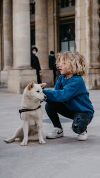 A young child with a dog sitting in front of classical columns in Paris, France.