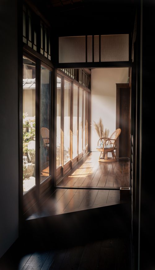 Free A serene sunlit hallway in a traditional Japanese home with wooden floors and large windows. Stock Photo