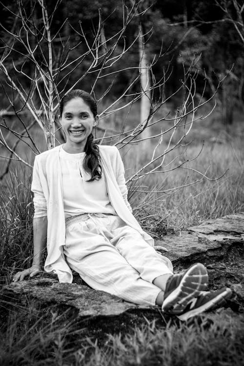 Free Grayscale Photo of a Woman Sitting on a Grassy Field Stock Photo