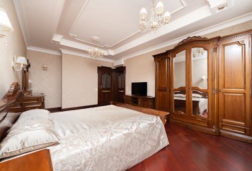 A Bed with White Linen Near the Wooden Cabinets