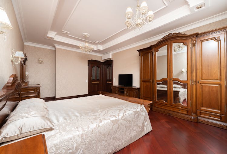 A Bed With White Linen Near The Wooden Cabinets