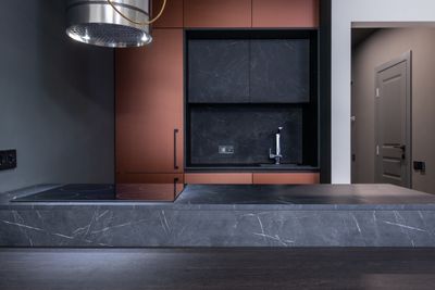 Kitchen island in dark veined stone with copper units — photo by Max Vakhtbovych on Pexels