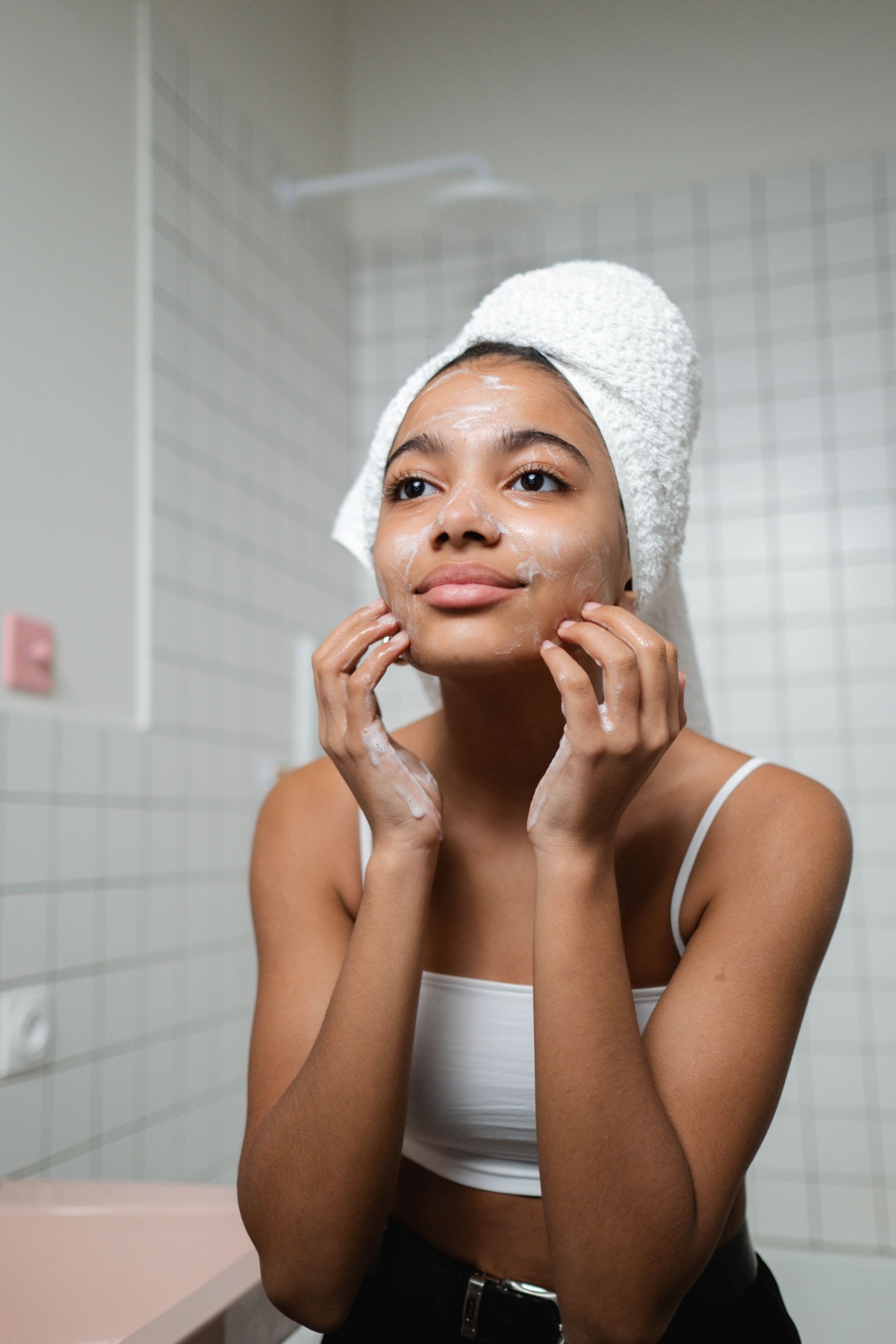 Woman gently cleansing her face during a skincare routine in a bright bathroom