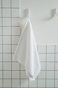 Simple white towel hanging in a contemporary bathroom with tiled wall.