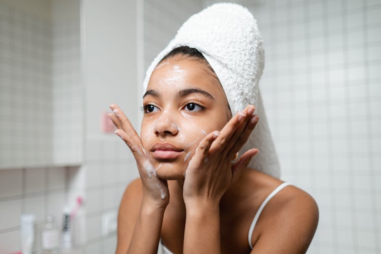 Woman In White Tank Top Washing Her Face With Soap