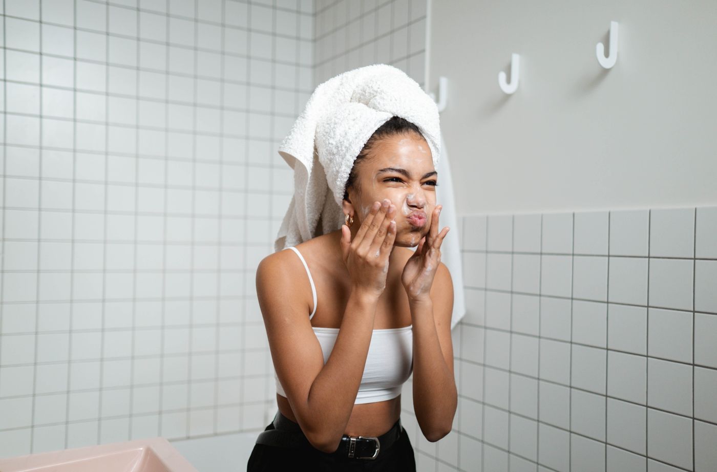 Woman applying facial cream as part of a bright bathroom skincare routine