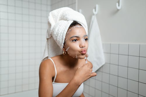 Free Woman With Cosmetic Mask Using A Facial Roller Stock Photo