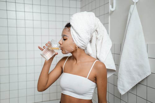 Woman in White Spaghetti Strap Top Drinking Water