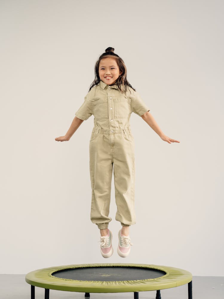 A Happy Little Girl Jumping On A Trampoline