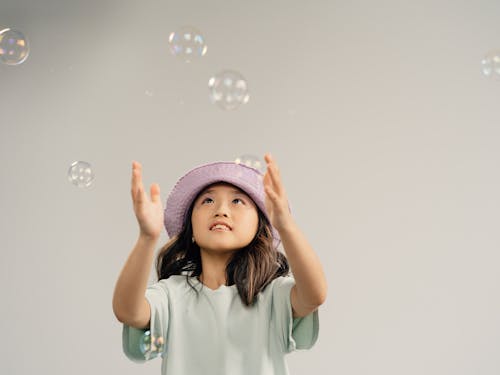 Young Girl Playing Bubbles on White Background
