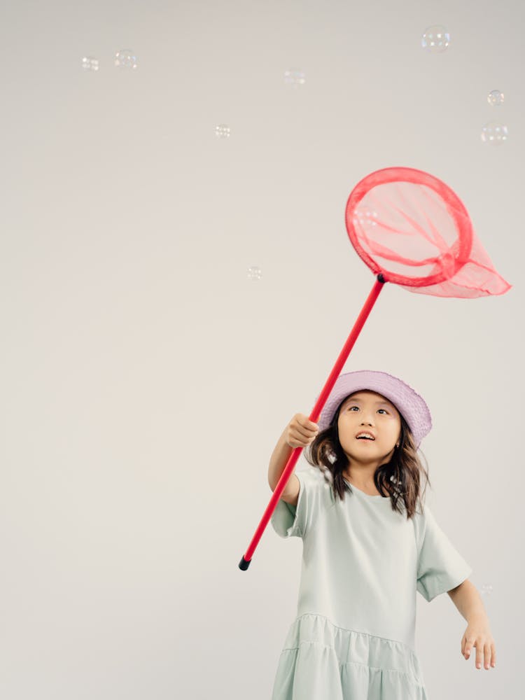 A Girl Catching Bubbles With Butterfly Net