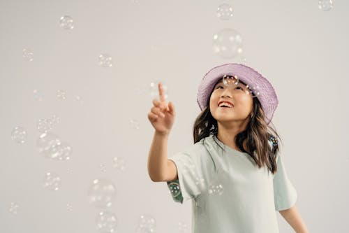 Young Girl Playing Bubbles on White Background