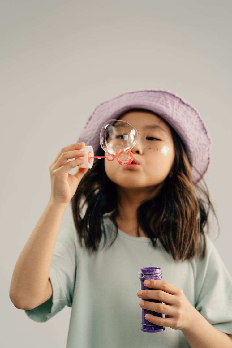 A Little Girl Playing With A Bubble Wand