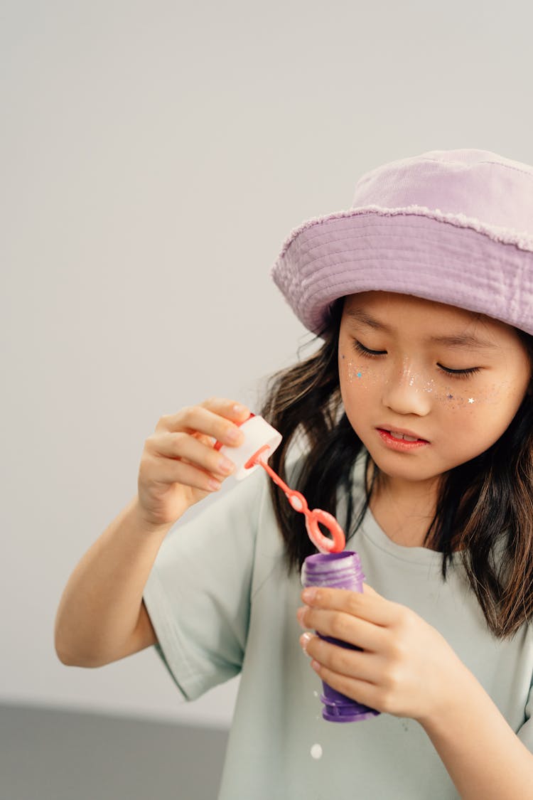 A Little Girl Playing With A Bubble Wand