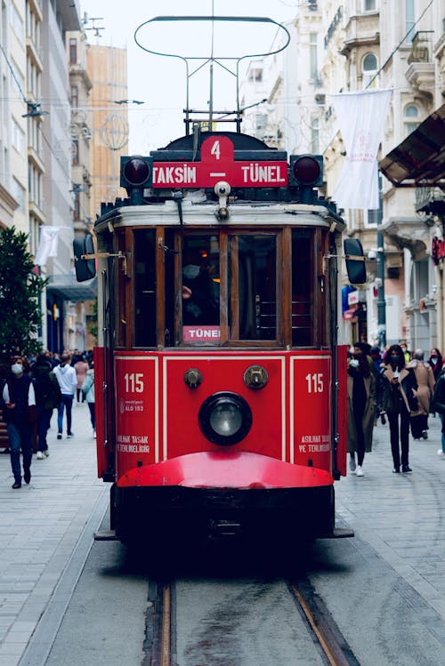 Red and Black Tram Between Buildings 