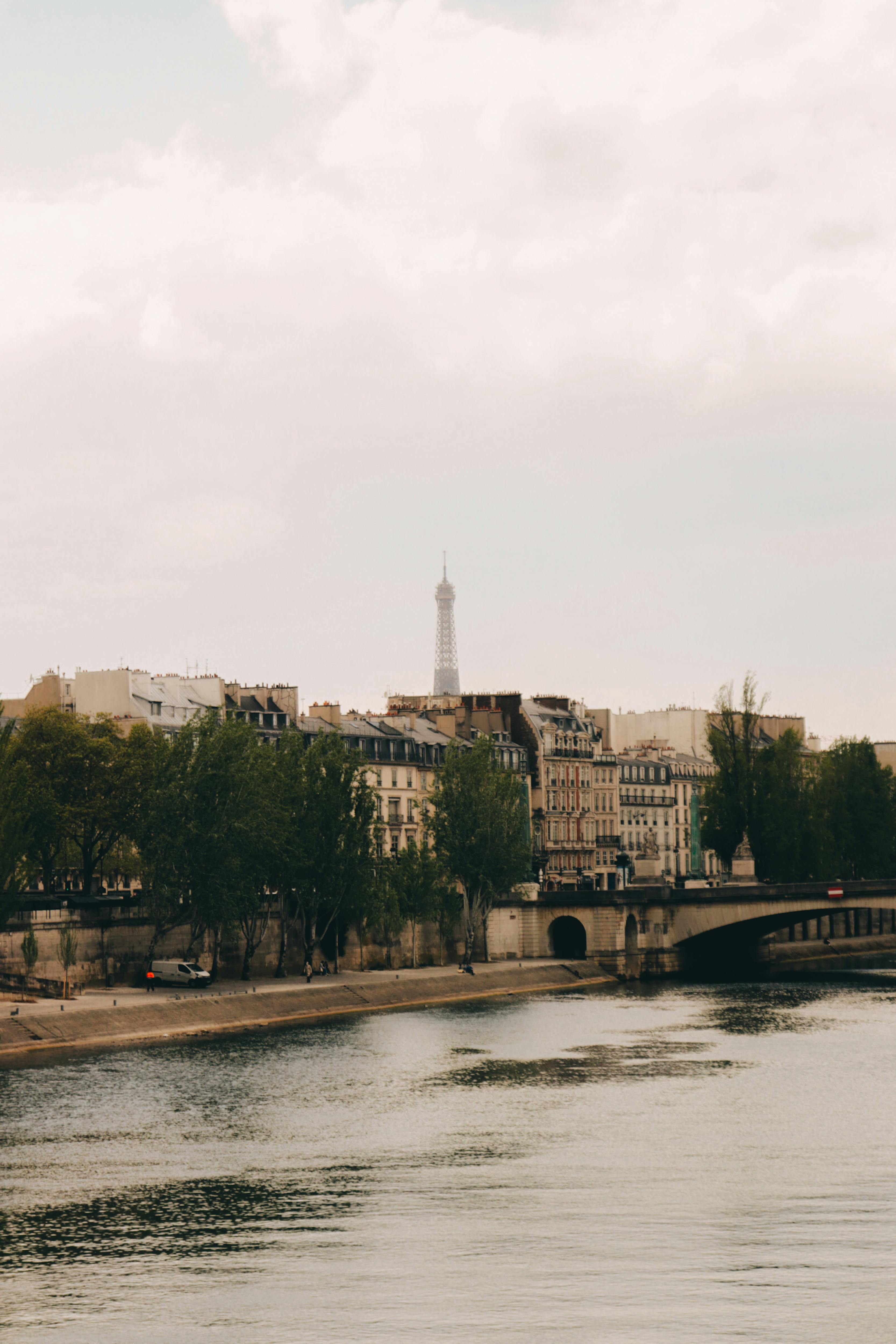 Scenic view of Paris with the Eiffel Tower and Seine River under a cloudy sky.