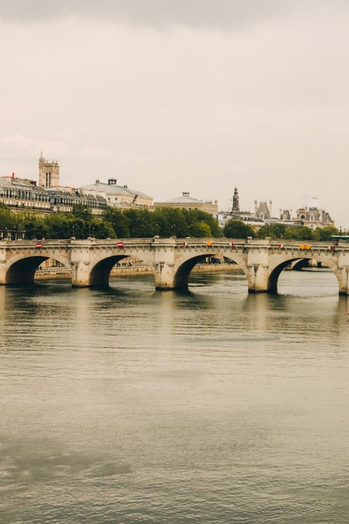 Free Elegant stone bridge over calm river in Paris with historic architecture. Stock Photo