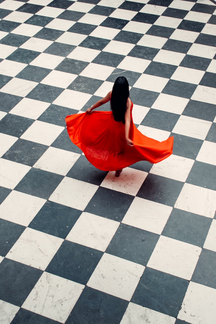 High-Angle Shot Of A Woman In Her Red Dress Dancing On Black And White Floor