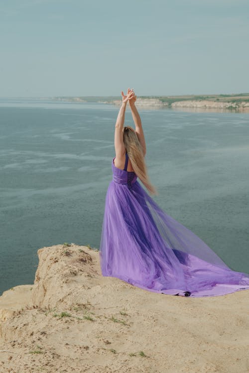 Woman in Purple Dress Standing on the Edge Near Body of Water