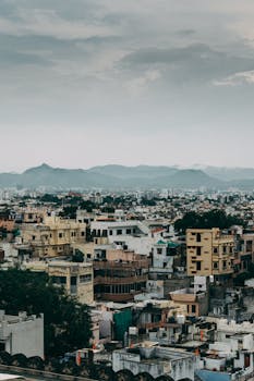 Discover the vibrant urban landscape of Udaipur, India, against a majestic mountainous backdrop.