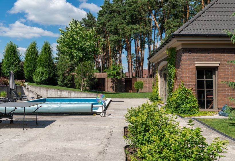 Backyard swimming pool beside a brick home