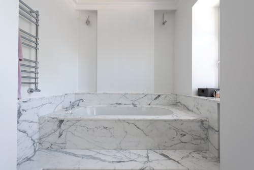 White Ceramic Bathtub in a Marble Finish Floor and Walls