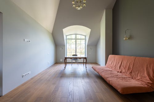 A Couch on a Wooden Floor with Table Near the Glass Window