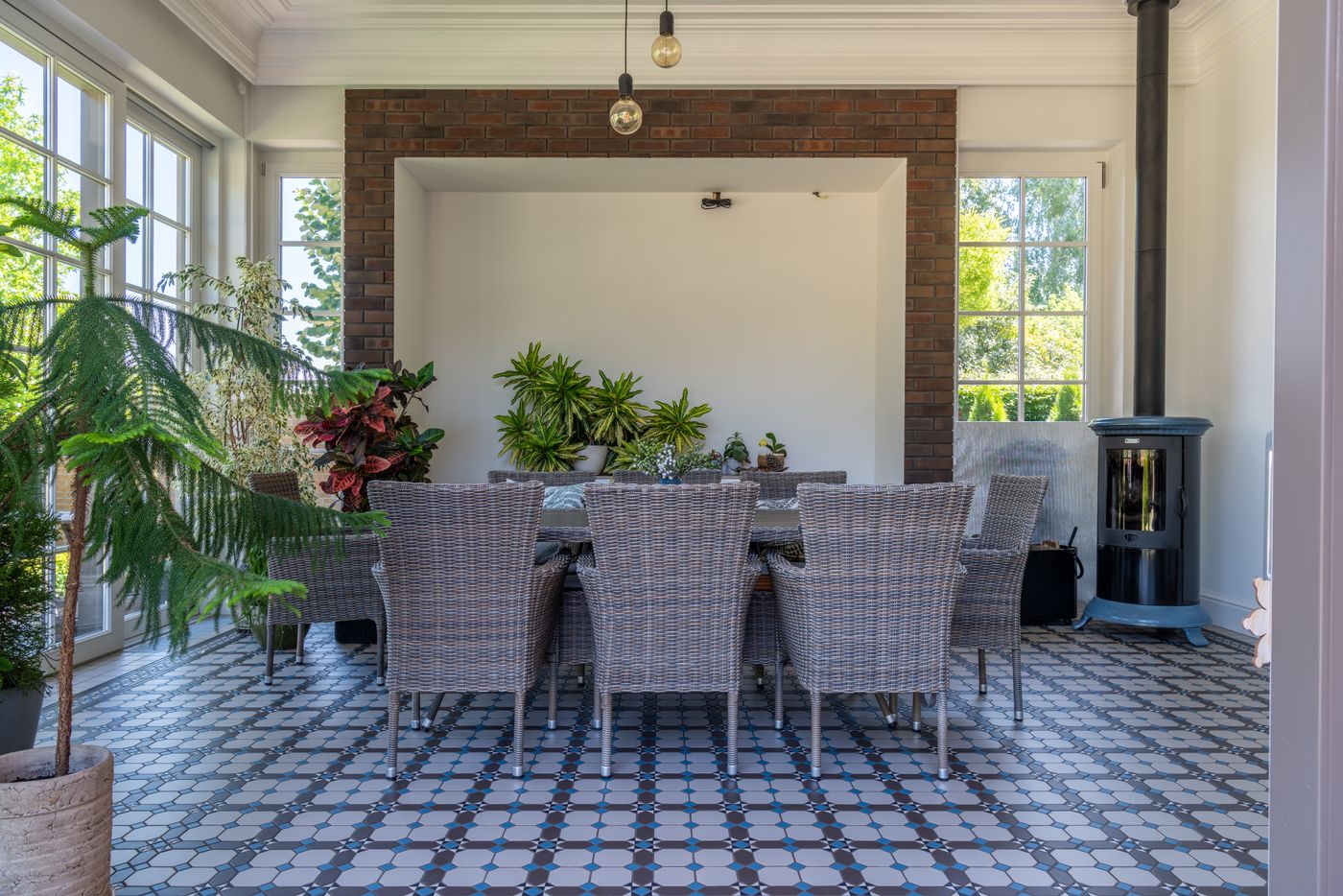 Dining room with wicker furniture and lush plants under a glazed roof