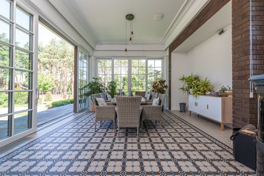 Bright sunroom with wicker chairs and patterned tile floor, ideal for relaxation.