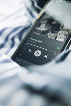 Close-up of a smartphone streaming music on a striped fabric background.