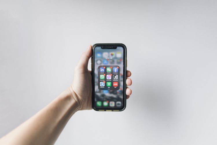 Hand Of A Person Holding A Smartphone Showing Home Screen