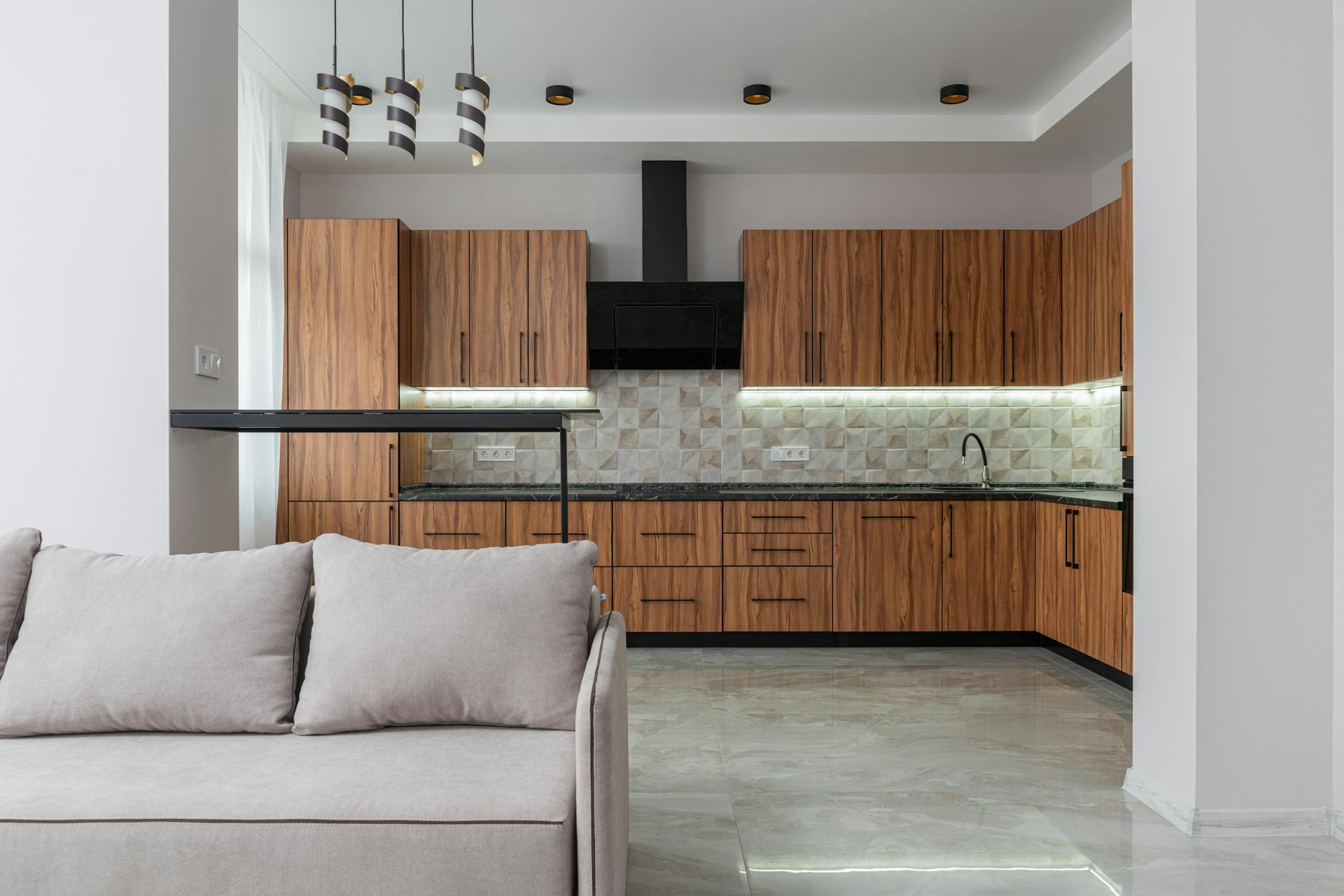 Elegant modern kitchen with wooden cabinets and a cozy sofa for a contemporary home interior.