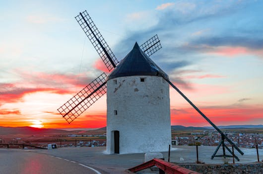 Capture of a scenic windmill in Consuegra, Spain with a vibrant sunset.