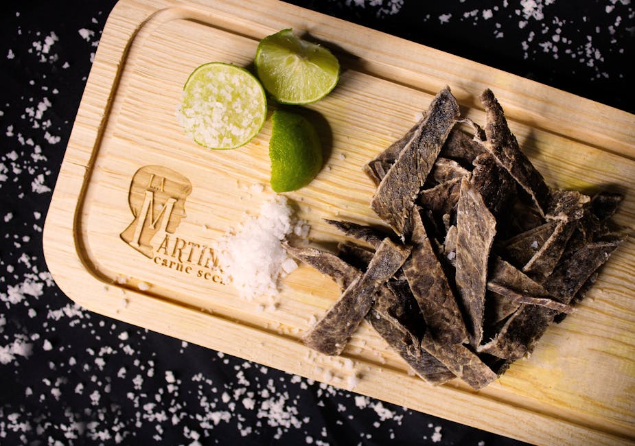 KitchenAid vs Cosori: Which Dehydrator Excels at Jerky and Dried Fruits? Top view of dried meat strips with lime and sea salt on a rustic wooden board.