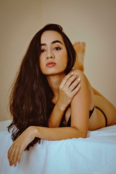 A woman with long hair poses in lingerie, highlighting sensual and seductive beauty.