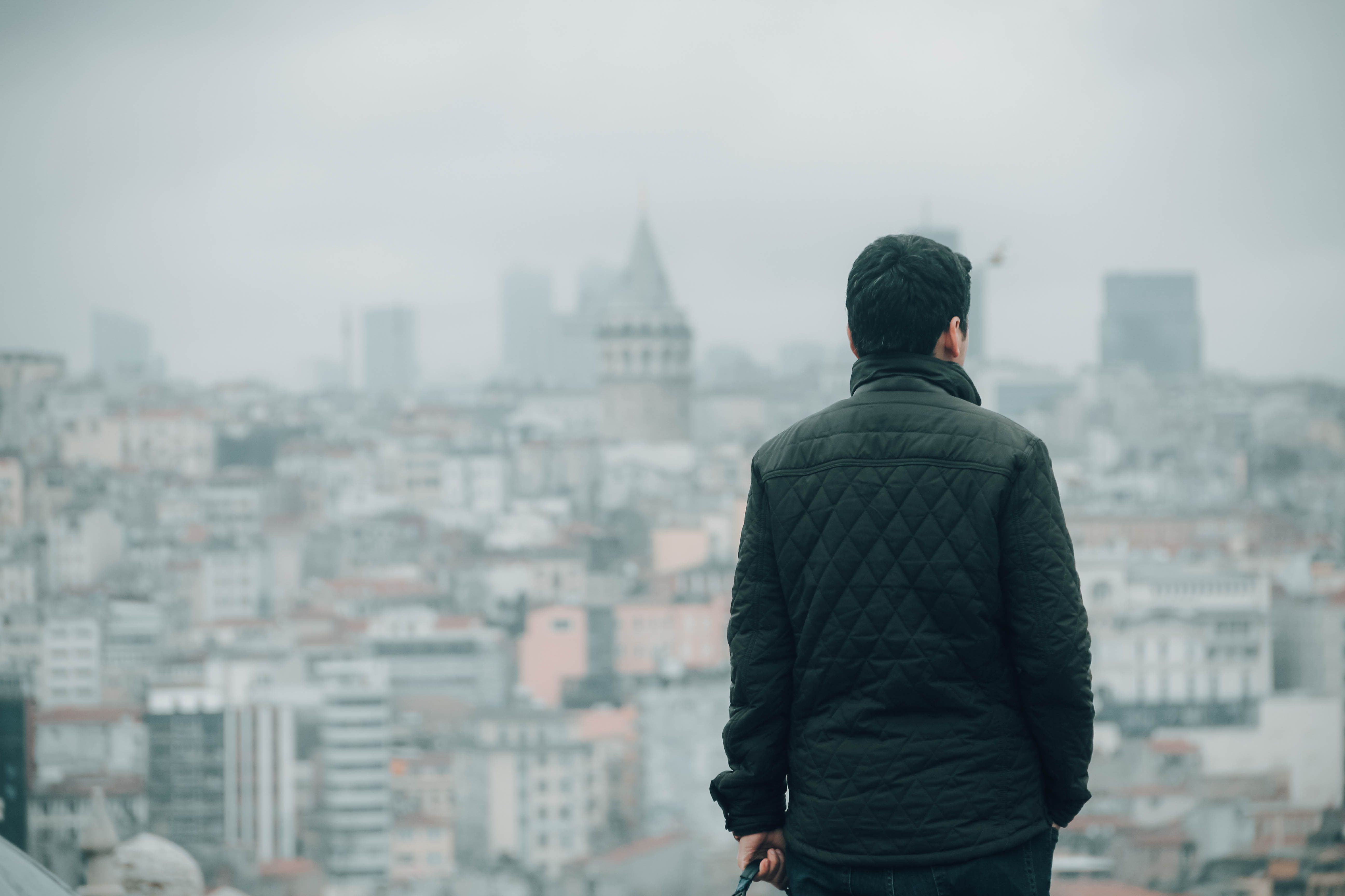 A man looks over a misty city skyline from a high vantage point.