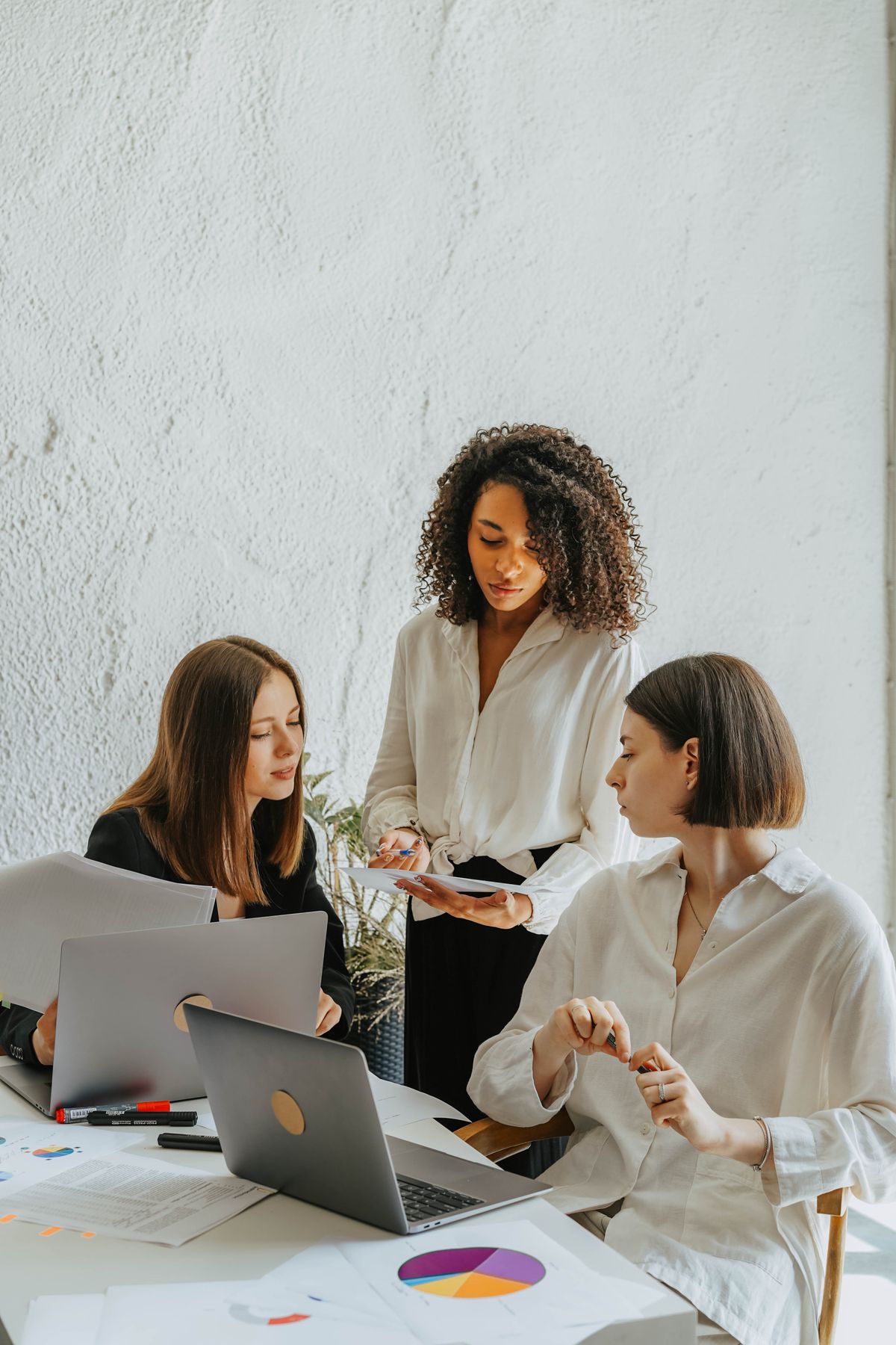 Women collaborating on a project with charts and laptops