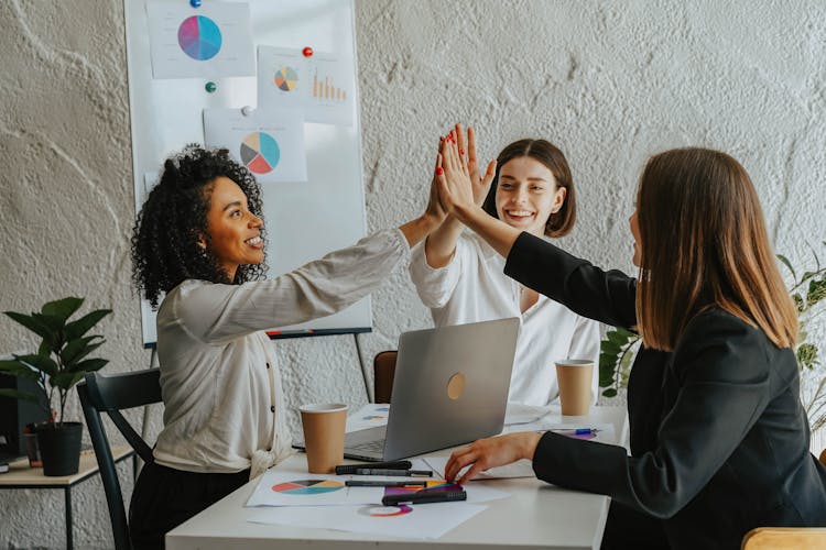 Beautiful Women Sitting At A Table Giving High Five