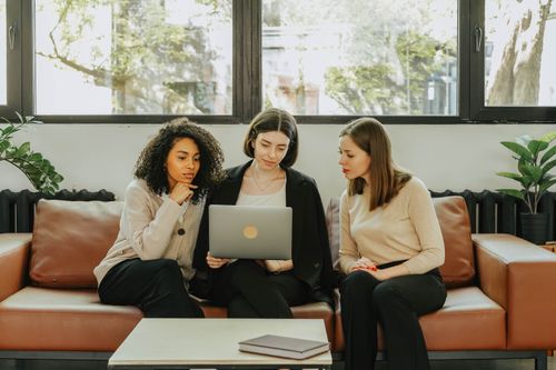 Free Three businesswomen collaborate on a laptop indoors, sharing ideas. Stock Photo